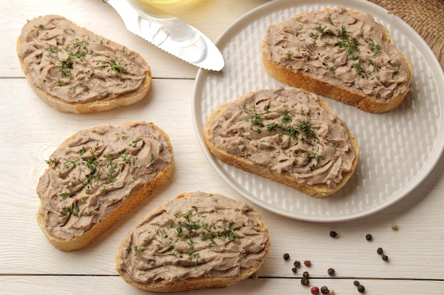 Paté di fegato di pollo fresco fatto in casa con erbe per il pane su un tavolo di legno bianco. Un panino. vista dall'alto