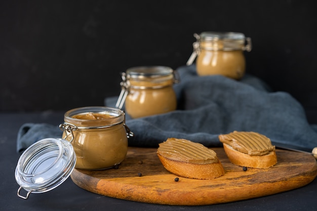 Patè di fegato in tre barattoli di vetro su uno sfondo scuro