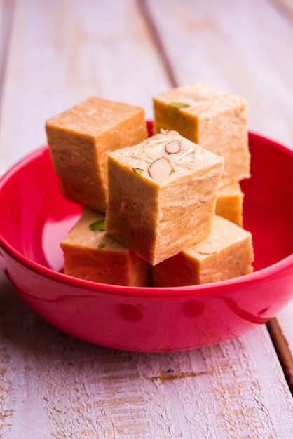 Patisa o Soan Papdi è un popolare dolce indiano a forma di cubo e croccante. Servito con mandorle e pistacchi in un piatto su sfondo lunatico. Messa a fuoco selettiva