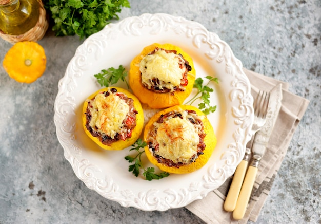 Patissons gialli biologici ripieni di carne, cipolle, carote, funghi e peperoncino al forno con formaggio.