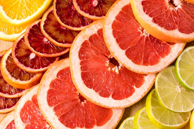 Pattern con fette fresche di diversi agrumi - arancio giallo e rosso, lime, limone e pompelmo. Distesi.
