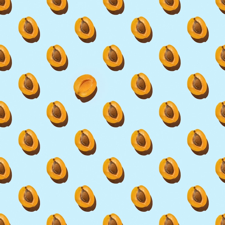 Photo pattern made with slices of fresh orange apricot isolated on a blue background, copy space