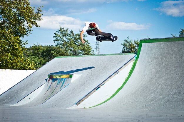 Pattinatore che sorvola lo skatepark in una mattina di sole