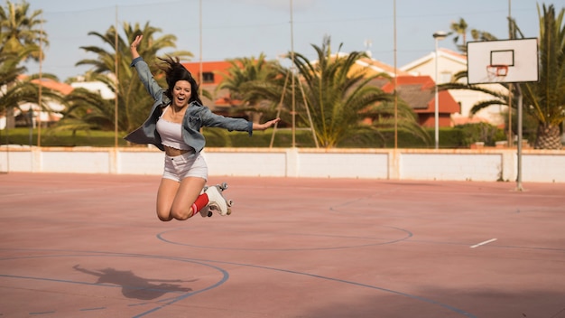 Pattinatore femminile che salta sopra il campo da calcio