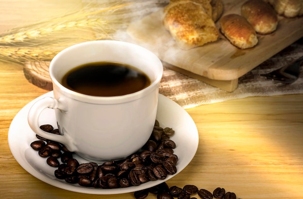 Pausa caffè al mattino tazza di caffè e chicchi di caffè tostati su un tavolo di legno con una luce solare