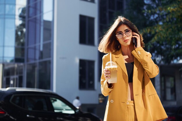 Pausa caffè Giovane donna alla moda in cappotto color bordeaux di giorno con la sua auto