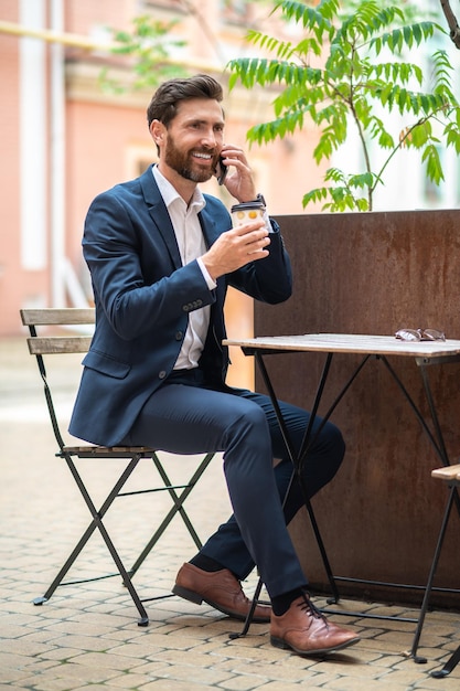 Pausa caffè. Giovane uomo d'affari bello che mangia caffè in un caffè della via