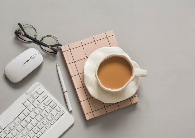 Pausa caffè in un ufficio a casa Lavoro di apprendimento sullo sfondo tastiera mouse notepad occhiali su uno sfondo grigio vista superiore