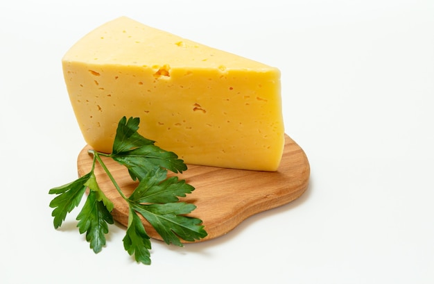 Pausa di formaggio e prezzemolo fresco su un tagliere di legno sulla superficie bianca