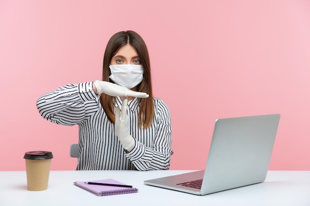 Pausa di quarantena Donna d'affari seduta al sicuro in buona salute con maschera igienica e guanti protettivi che mostrano un gesto di timeout stop sufficiente segno Lavorando in autoisolamento focolaio di coronavirus al chiuso