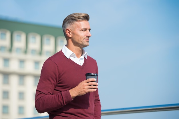 Pausa mattutina. Il ragazzo caucasico beve il caffè al mattino. Bell'uomo tenere tazza da asporto all'aperto. Buongiorno abitudine di routine. Mattinata in città.