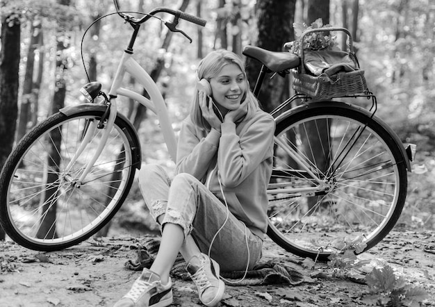 Pausa musicale goditi il relax ragazza della foresta in bicicletta per il divertimento calda ragazza autunnale con bicicletta e cuffia