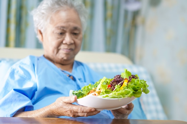 Paziente asiatico anziano o anziano della donna anziana che mangia alimento sano di verdure della prima colazione