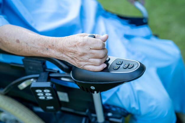 Paziente asiatico anziano o anziano su sedia a rotelle elettrica con telecomando in reparto di cura, concetto medico sano e forte