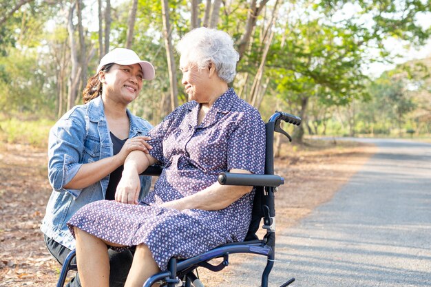 Paziente asiatico della donna maggiore sulla sedia a rotelle nel parco.