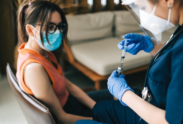 Paziente di donna caucasica che viene vaccinato contro il coronavirus che riceve il vaccino covid. Iniezione intramuscolare durante l'appuntamento dal medico in ospedale. Vaccinazione Covid-19.