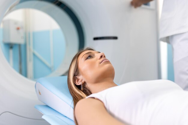 Paziente di sesso femminile sdraiata su un letto di scansione TC o PET o MRI che si muove all'interno della macchina mentre esegue la scansione del cervello e dei parametri vitali