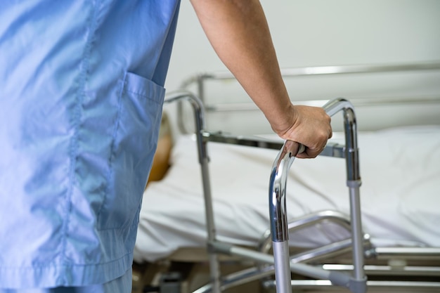 Paziente di signora asiatica che indossa cintura di supporto per il dolore alla schiena per lombare ortopedico con camminatore