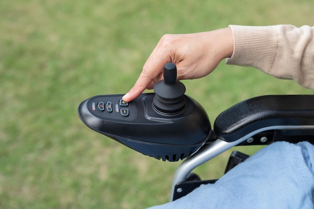 Paziente donna asiatica su sedia a rotelle elettrica con comando joystick in ospedale