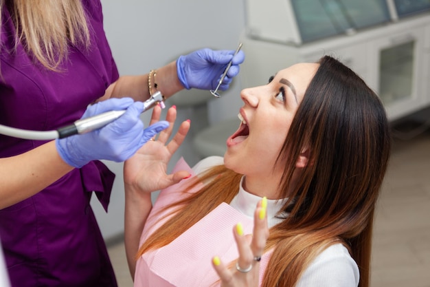 Paziente donna spaventata durante l'esame dal dentista nella clinica dentale Paura dei dentisti