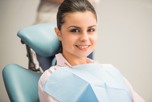 Paziente femminile castana adulto che sorride nell'odontoiatria.