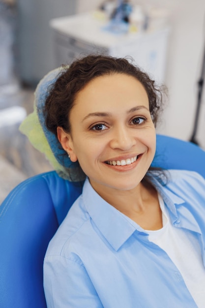 Paziente femminile positivo che visita il dentista e sorride alla macchina fotografica nella clinica moderna