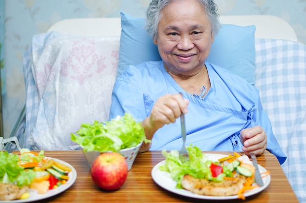 Paziente senior asiatico della donna della signora anziana che mangia alimento sano della prima colazione in ospedale.