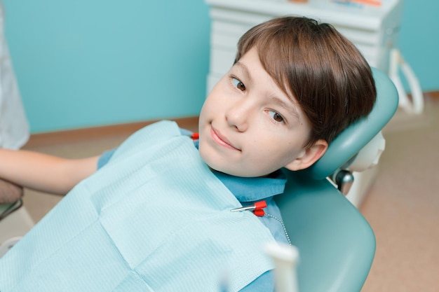 Paziente sulla poltrona del dentista Ragazzo adolescente che ha un trattamento dentale presso l'ufficio del dentista