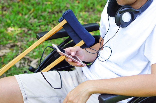 Pazienti o disabili seduti su una sedia a rotelle che indossano le cuffie e hanno una stampella sul lato