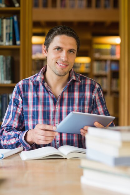 PC maturo felice della compressa della tenuta dello studente nella biblioteca