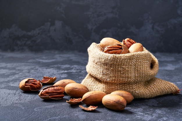 Pecan in borsa sul tavolo nero. Mucchio o pila di noci pecan.