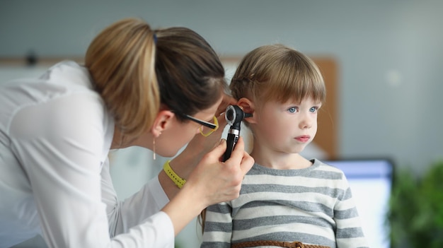 Pediatra che osserva l'orecchio di una bambina usando un otoscopio in clinica