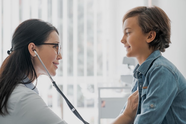 Pediatra in camice bianco esame ragazzo con stetoscopio in clinica medica