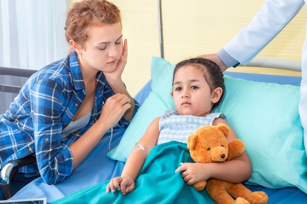 Pediatra (medico), madre rassicurante e discutendo di sua figlia. Ragazza paziente triste sull'ospedale della camera da letto.