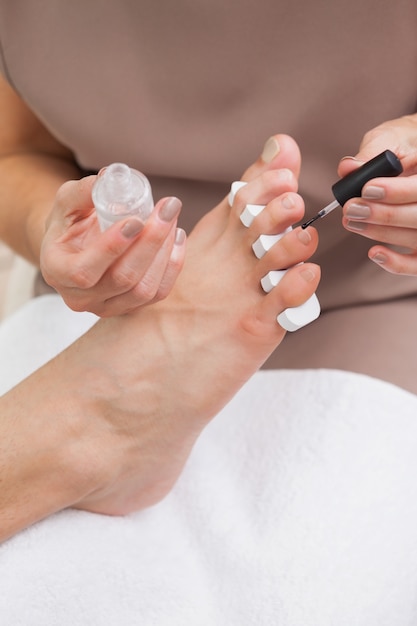 Pedicurista che dipinge unghie dei clienti