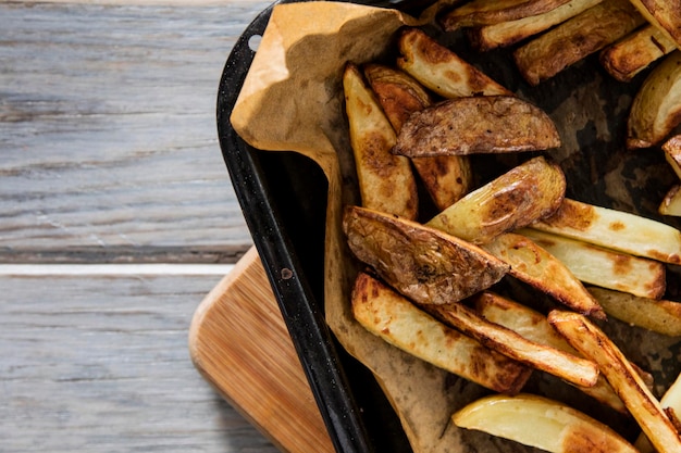 Pelle al forno fatta in casa su patatine fritte su uno sfondo di legno rustico