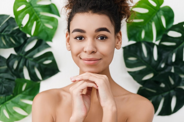 Pelle perfetta. Donna sensuale contro le foglie tropicali, che guarda l'obbiettivo