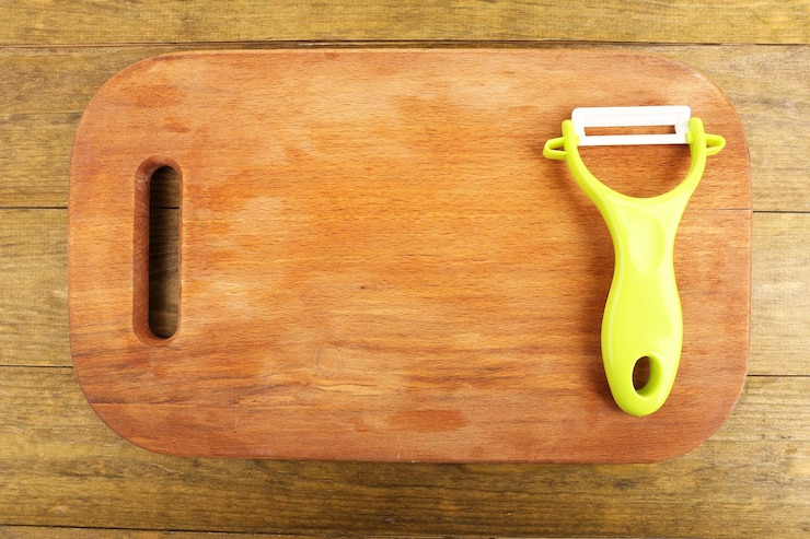 Foto peller vegetale e tagliere sulla tavola di legno