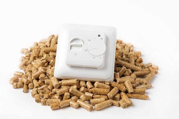 Pellet di legno con termostato Testa valvola termostatica isolata su sfondo bianco Fonte rinnovabile di riscaldamento Biocombustibile Combustibile ecologico ricavato da biomassa La fonte di energia alternativa Crisi del gas