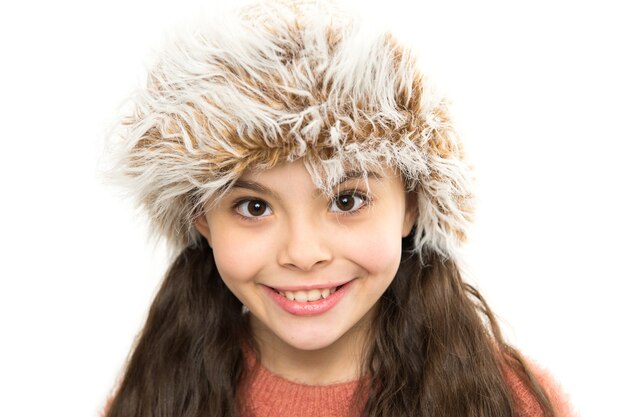 Pelliccia fantasia. Comodo outfit invernale. Cappello di usura del bambino. Stai al caldo questo inverno. Bambina felice nella moda invernale. Piccolo bambino sorridente in cappello di pelliccia sfondo bianco. Il modello carino gode dello stile invernale.