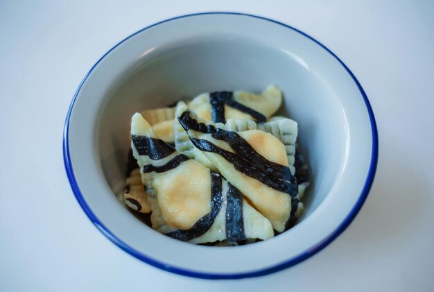 Pelmeni russi cucinati preparati in casa ravioli con carne su piatto grigio con pepe di prezzemolo fresco sfondo rustico in legno Vista superiore