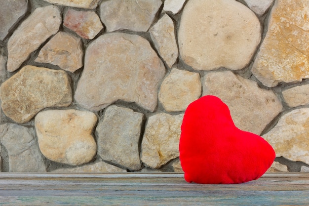 Peluche cuore rosso sullo sfondo di un muro di pietra, il concetto di amore e romanticismo