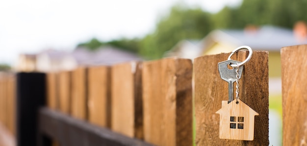 Pendente in legno di una casa e chiave su una recinzione