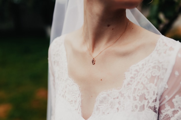 Pendente in oro al collo della sposa in abito bianco con velo