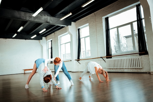 Pendenza profonda. Due simpatiche ragazze con i capelli lunghi della generazione Z che si allenano in studio mentre si esercitano in una profonda inclinazione