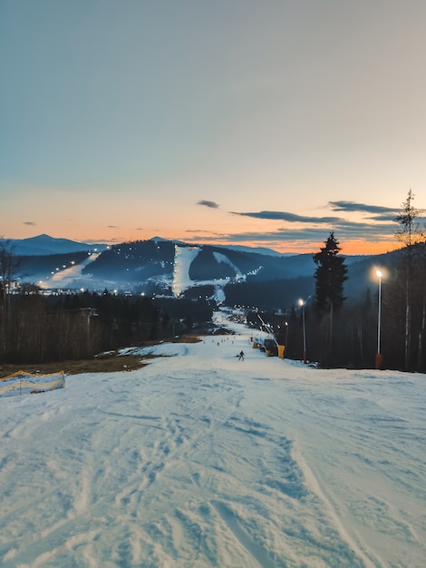 Pendio invernale al tramonto del paesaggio delle montagne