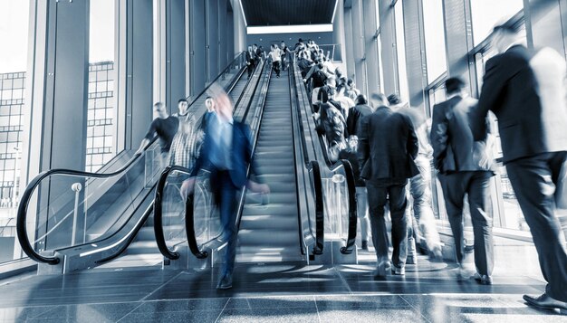 Pendolari sfocati che corrono sulle scale mobili a una fiera. ideale per layout di siti web e riviste
