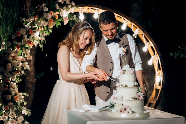 Pengantin baru dengan gembira memotong, tertawa, dan mencicipi kue pernikahan