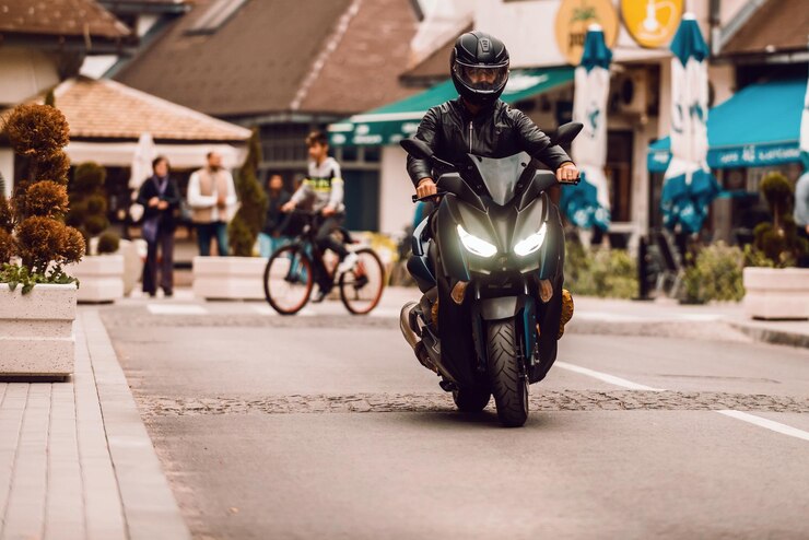Pengendara motor modern mengendarai sepeda motor di jalan di kota Fokus selektif