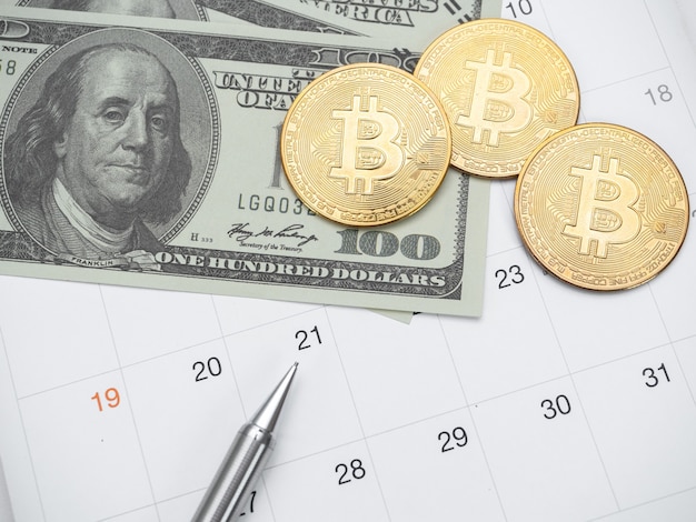 Penna del dollaro dei soldi e bitcoin dell'oro sul calendario